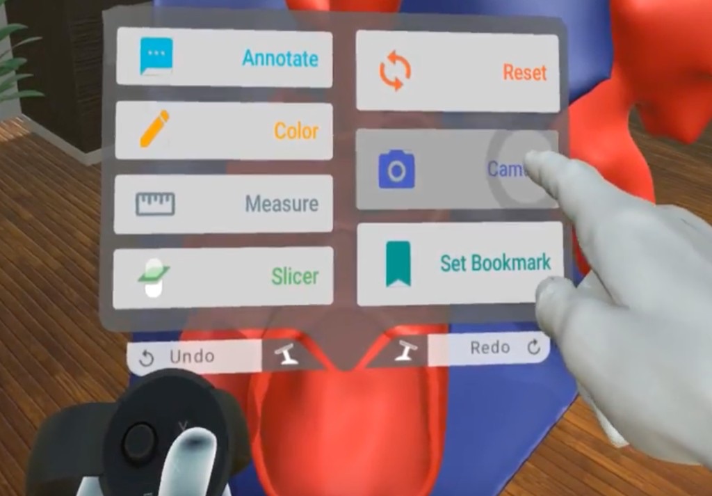 Hand pointing at a floating VR tool menu (annotate, color, measure, slicer, reset, camera, set bookmark) beside a heart model